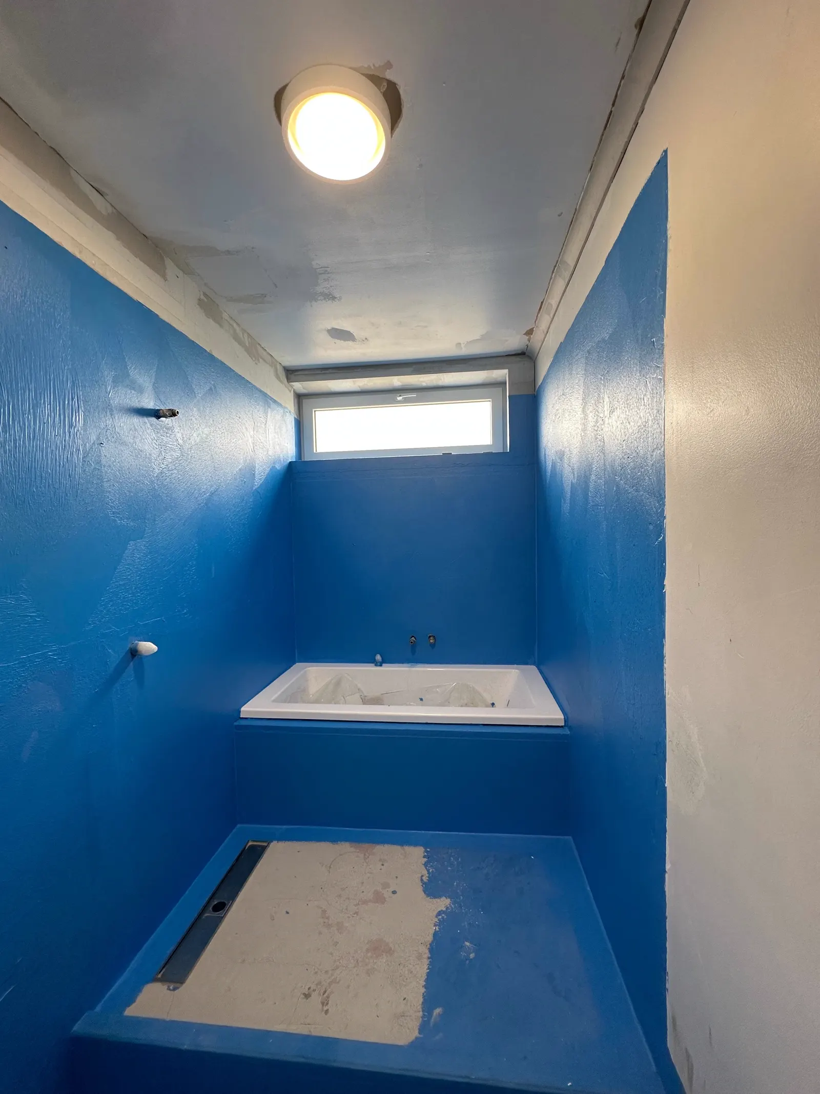 Bathroom with waterproofing membrane applied across the floor and walls, ready for tiling