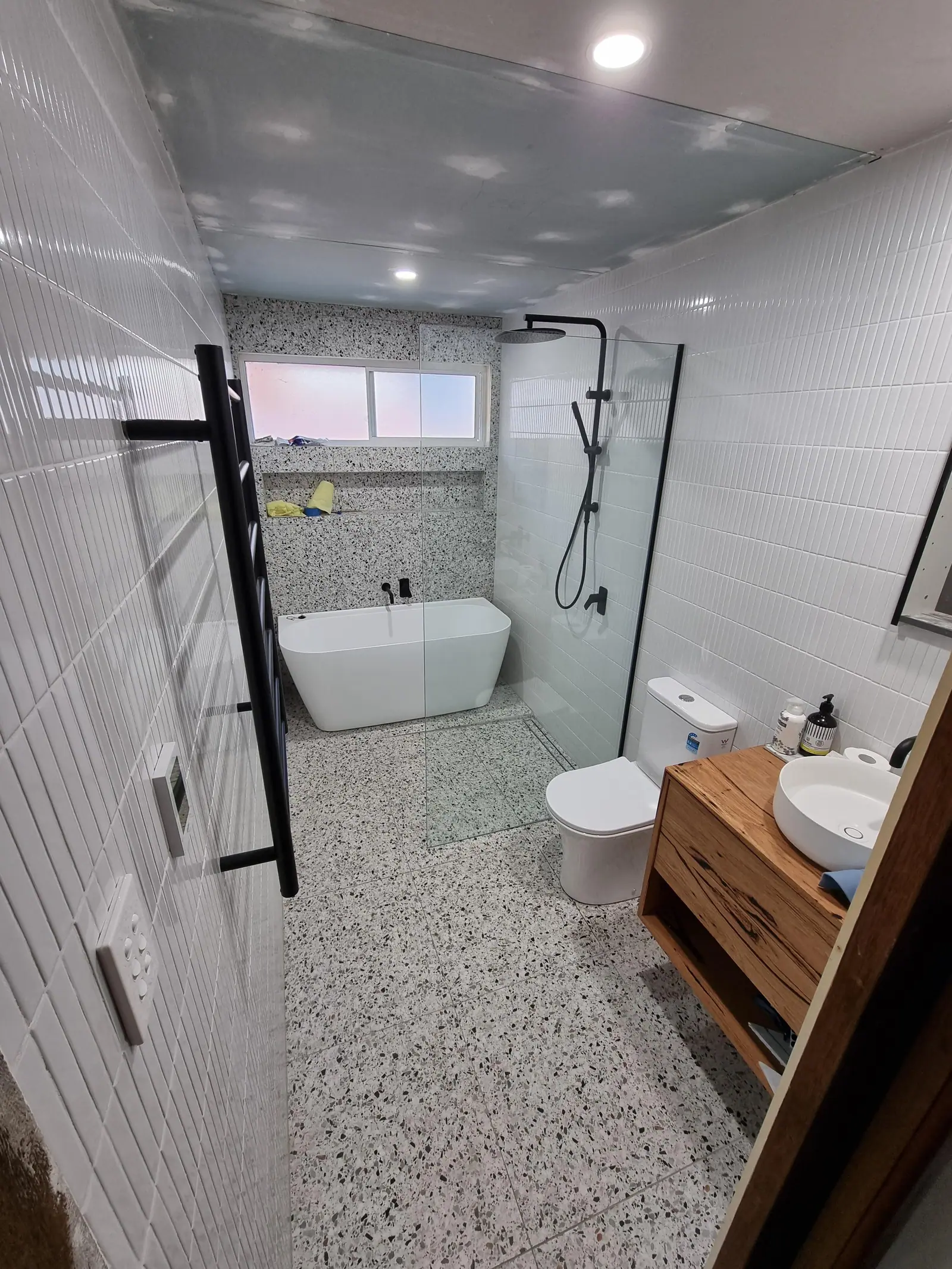 Completed bathroom with terrazzo-look floor tiling, a freestanding bath and a walk-in shower